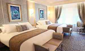 Ylellisesti sisustettu hotellihuone kahdella parivuoteella, tyylikkäillä huonekaluilla ja seinäkoristeilla. (Tekoälyn luoma teksti)