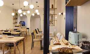 Ruokasali, jossa pöytiä, tuoleja ja buffet-pöytä, jossa leipää ja lisukkeita. (Tekoälyn luoma teksti)