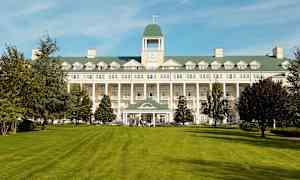 Kuva suuresta rakennuksesta, jonka edustalla on nurmikenttä. (Tekoälyn luoma teksti)