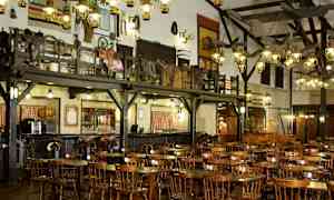 Rustiikkisen ravintolan sisustus, jossa on puupöytiä ja tuoleja sekä koristeita seinillä. (Tekoälyn luoma teksti)