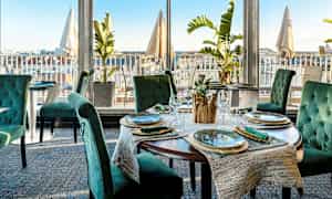 Ravintola, jossa on tyylikkäästi katetut pöydät ja näkymä kaupunkiin. (Tekoälyn luoma teksti)