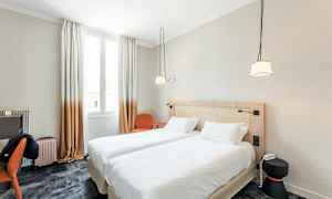 Hotellihuone, jossa on kaksi yhdistettyä erillissänkyä, kirjoituspöytä, tuoli ja ikkuna valon tuomiseksi. (Tekoälyn luoma teksti)