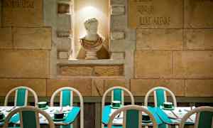 Kuvassa on ravintola, jossa on turkooseja pöytiä ja tuoleja sekä valkoinen veistos seinän syvennyksessä. (Tekoälyn luoma teksti)