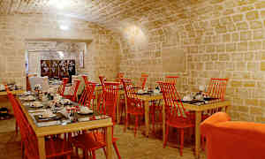 Ruokasali, jossa kiviholvikatto, punaiset tuolit ja katetut pöydät. (Tekoälyn luoma teksti)