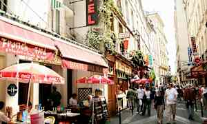 Vilkaskatu kaupungissa, jossa on ulkokahviloita ja eri ravintoloiden sekä hotellien kylttejä. (Tekoälyn luoma teksti)