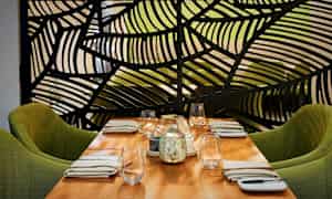 Katettu pöytä, jossa on vihreät tuolit ja koristeellinen näyttö taustalla. (Tekoälyn luoma teksti)