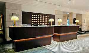 Hotellin aulan vastaanottotiski, jossa on marmoripinnat ja pöytälamput. (Tekoälyn luoma teksti)