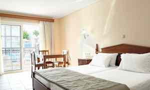 Hotellihuone, jossa on kaksi sänkyä, puupöytä ja tuolit sekä parveke, josta on näkymä uima-allasalueelle. (Tekoälyn luoma teksti)