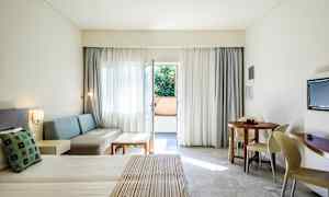 Hotellihuone, jossa on pedattu sänky, oleskelualue, pyöreä ruokapöytä ja parvekkeen ovi. (Tekoälyn luoma teksti)