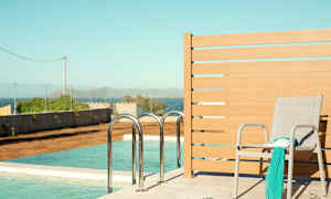 Aurinkotuoli, jonka päällä huivi ja kirja, sijaitsee uima-altaan vieressä, merinäköalalla. (Tekoälyn luoma teksti)