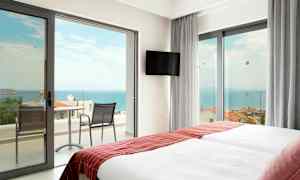 Hotellihuone, jossa kaksi sänkyä ja ovet parvekkeelle, josta näkymä merelle. (Tekoälyn luoma teksti)