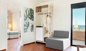 Moderni hotellihuone, jossa istuimet, avoin vaatekaappi ja merinäköala. (Tekoälyn luoma teksti)