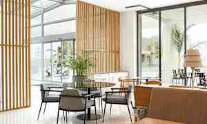 Moderni huoneen sisustus, jossa on pöytiä, tuoleja ja ikkunoita. (Tekoälyn luoma teksti)