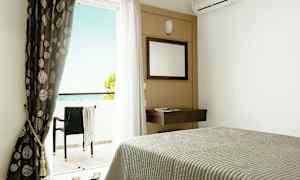 Hotellihuone, jossa sänky, peili, verhot ja parveke merinäköalalla. (Tekoälyn luoma teksti)