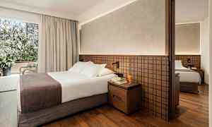 Hotellihuone, jossa parivuode, yöpöytä ja vaatekaappi. (Tekoälyn luoma teksti)