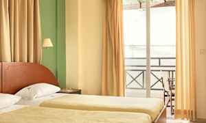 Hotellihuone, jossa kaksi yhden hengen sänkyä, verhot ja parveke. (Tekoälyn luoma teksti)