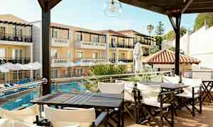 Hotellirakennus parvekkeineen ja aurinkovarjoineen uima-altaan äärellä, etualalla istumaryhmiä. (Tekoälyn luoma teksti)