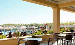 Ulkoterassi, jossa pöytiä ja tuoleja, näkymä altaalle ja aurinkotuoleille. (Tekoälyn luoma teksti)