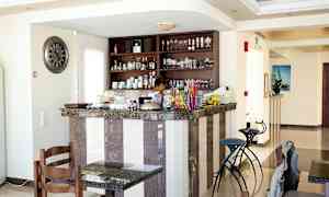 Kahvila- tai baari-alue, jossa on marmorinen tiski, tuoleja ja hyllyjä täynnä laseja ja posliinia. (Tekoälyn luoma teksti)