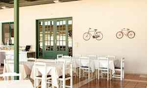 Ruokailutila, jossa on pöytiä ja tuoleja, vihreä ovi ja seinälle ripustettuja pyöräkoristeita. (Tekoälyn luoma teksti)