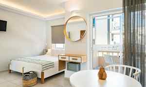 Nykyaikaisesti sisustettu hotellihuone, jossa sänky, peili ja parvekkeen ovi. (Tekoälyn luoma teksti)