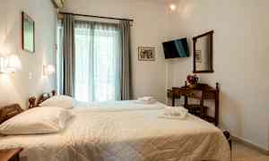 Hotellihuone, jossa on kaksi erillistä sänkyä, televisio, verhoilla varustettu ikkuna ja puupeili. (Tekoälyn luoma teksti)