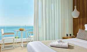 Näkymä huoneesta, jossa on pedattu sänky, parvekkeelle tuoleineen ja pöytineen sekä merinäköalalle. (Tekoälyn luoma teksti)