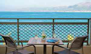 Kaksi tuolia pöydän ääressä, jossa on kannu ja kaksi lasia, näkymä merelle. (Tekoälyn luoma teksti)