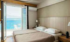 Hotellihuone, jossa kaksi erillistä vuodetta ja avoin parvekkeen ovi, joka avautuu merelle. (Tekoälyn luoma teksti)