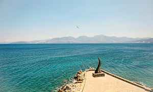 Kivinen ranta ja meri, jossa näkyy taideteos laiturilla. (Tekoälyn luoma teksti)