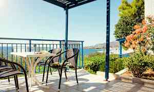 Terassi, jossa tuoleja ja pöytä, merinäköala ja vehreä ympäristö. (Tekoälyn luoma teksti)