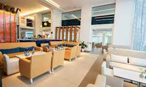 Hotellin aula, jossa istuinryhmiä, pöytiä ja moderni sisustus. (Tekoälyn luoma teksti)