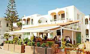 Valkoinen rakennus, jossa ulkobaaria ja istuinpaikkoja. (Tekoälyn luoma teksti)