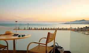 Näköala terassilta merelle, taustalla auringonlasku ja rantavarjot. (Tekoälyn luoma teksti)