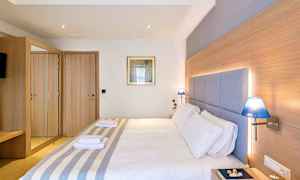 Hotellihuone, jossa on parivuode, puisia yksityiskohtia, sinisiä lamppuja ja peilikaappi. (Tekoälyn luoma teksti)