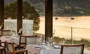 Terassi, jossa on katetut pöydät rannalla ja näkymä merelle. (Tekoälyn luoma teksti)