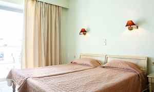 Kaksi erillistä sänkyä, joissa on vaaleanpunaiset peitot, huoneessa jossa on ikkuna ja seinävalaisimia. (Tekoälyn luoma teksti)