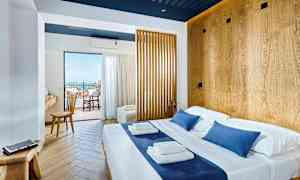 Valoisa hotellihuone, jossa on parivuode ja puuyksityiskohtia, näkymä parvekkeelle ja merelle. (Tekoälyn luoma teksti)