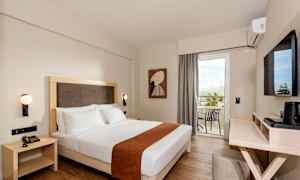 Hotellihuone, jossa on parisänky, seinälle kiinnitetyt valaisimet ja parveke näkymällä. (Tekoälyn luoma teksti)