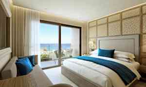 Hotellihuone, jossa parivuode, sohva ja parvekkeelta avautuvat näkymät merelle. (Tekoälyn luoma teksti)