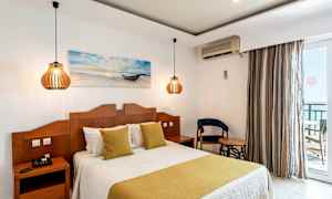 Hotellihuone, jossa on parivuode, kaksi yöpöytää lampuilla ja tuoli pöydän vieressä. (Tekoälyn luoma teksti)