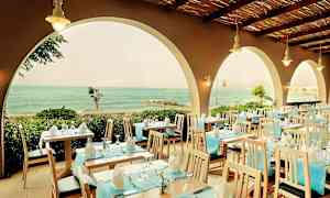 Ravintola, jossa katettuja pöytiä ja näkymä merelle kaarien läpi. (Tekoälyn luoma teksti)