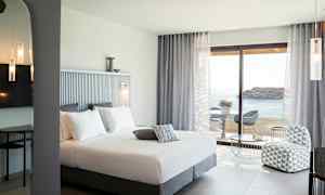 Hotellihuone, jossa on parisänky, istuinryhmä ja merinäköala. (Tekoälyn luoma teksti)