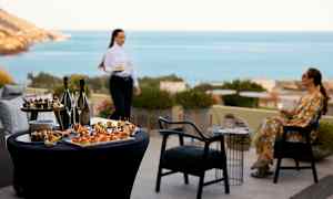 Pöytä, jossa alkupaloja ja juomia, taustalla merinäkymä. (Tekoälyn luoma teksti)