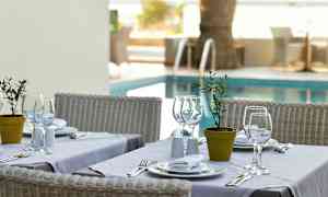 Katettu pöytä, jossa on valkoisia lautasia ja laseja, sijoitettuna altaan viereen. (Tekoälyn luoma teksti)