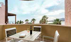 Näköala terassilta, jossa on pöytä ja tuolit sekä viinipullo ja lasi. (Tekoälyn luoma teksti)