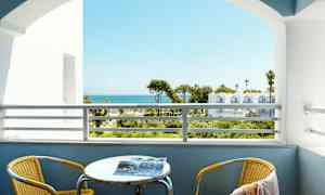 Näköala parvekkeelta merelle taustalla. Parvekkeella on keltainen tuoli ja pöytä. (Tekoälyn luoma teksti)