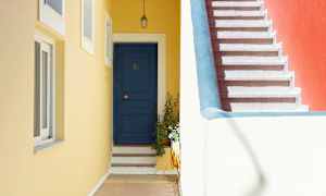 Sininen ovi askelmilla ja keltainen seinä portaiden vieressä, joissa on punainen seinäosa. (Tekoälyn luoma teksti)