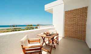 Parveke, jossa puupöytä ja kaksi tuolia, merinäköala taustalla. (Tekoälyn luoma teksti)