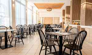 Valoisa ja ilmava kahvila, jossa mustia tuoleja ja pöytiä. (Tekoälyn luoma teksti)